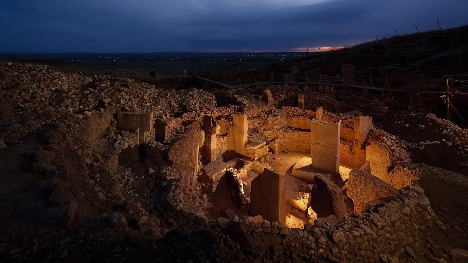 Photo de nuit du site de Göbekli Tepe, un cercle de pierre éclairé par quelques lampes